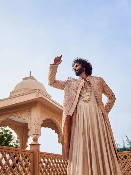A dynamic shot capturing the flowing Angarkha-style cut of the inner kurta beneath the embroidered sherwani jacket. This adds a touch of drama and traditional flair.