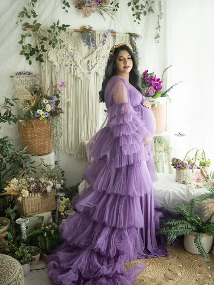 A full-length portrait showcasing the beautiful details of the lavender tulle gown. The side lighting from the window adds a soft, natural glow.