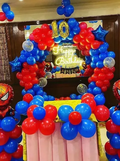 A vibrant Spider-Man theme for a 10th birthday celebration. This setup features a balloon arch in bold red and blue, a "Happy Birthday" neon sign, the number '10' in gold foil balloons, and two large Spider-Man character balloons standing guard.