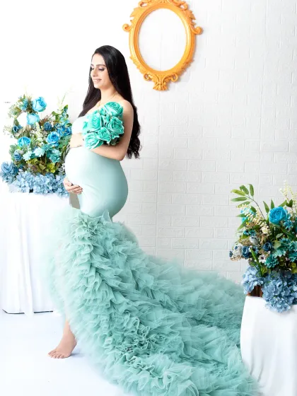 A beautiful standing portrait in a stunning mint green ruffled gown. The surrounding blue flowers complement the dress perfectly, creating a cohesive and elegant look.