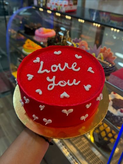 A simple and sweet "Love You" cake. The bright red color and scattered white hearts make it a perfect, straightforward expression of affection for any occasion.