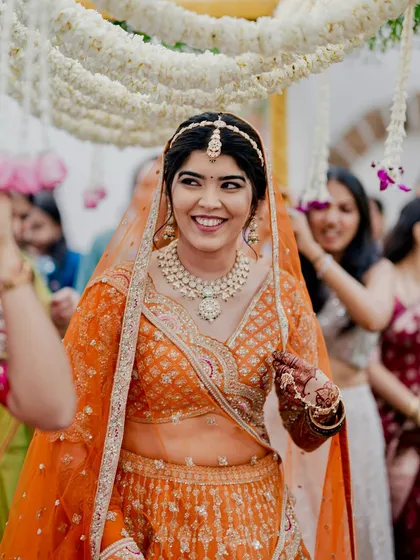 Reeya's joyful entrance. Her smile lights up the frame, and her makeup enhances her happiness, making her look every bit the radiant bride.