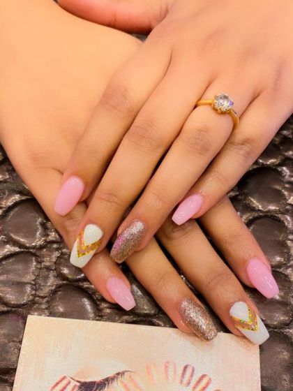 A lovely pink and white set with gold accents. The design includes a gold glitter nail and white accent nails with a gold chevron pattern.