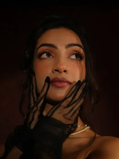 A close-up portrait that captures a dreamy, thoughtful expression. The soft lighting and the classic makeup application work together to create a painterly, artistic feel.