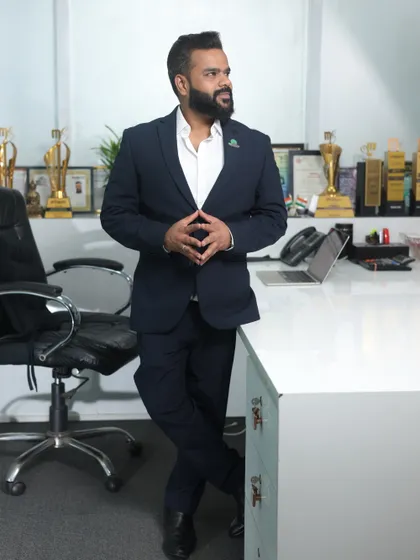 A confident standing portrait of me in the office, surrounded by the tools of my trade and the awards we have earned. This represents the blend of creativity and business acumen that defines my brand.