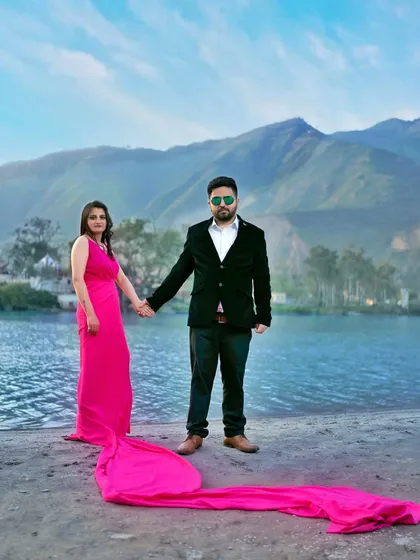 A full-length portrait of the couple holding hands by the river, with the bride's long dress trailing behind her. This shot captures both the couple and the beautiful scenery.