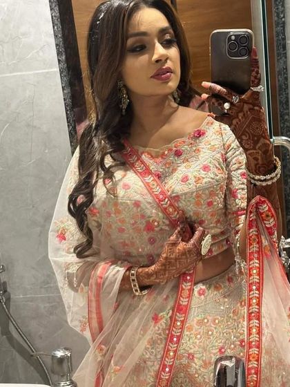 A mirror selfie showing off the intricate floral work on the blouse of this popular pink rental lehenga.
