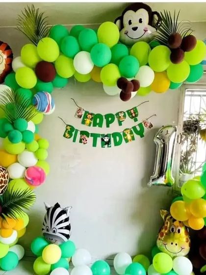 A jungle safari theme for an 11th birthday, featuring a green and yellow balloon arch with animal print and character foil balloons.