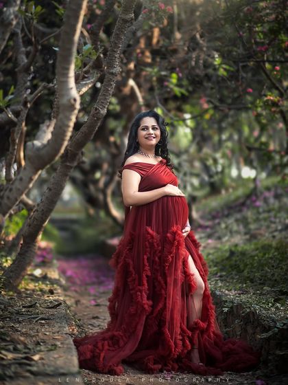 A fairytale moment in an enchanted forest. The rich red gown stands out beautifully against the lush greenery and fallen petals.