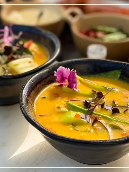 We are committed to using only high-quality, organic ingredients. This vibrant yellow curry, garnished with an edible flower and microgreens, is a testament to our promise of delivering fresh, flavorful, and visually stunning food.
