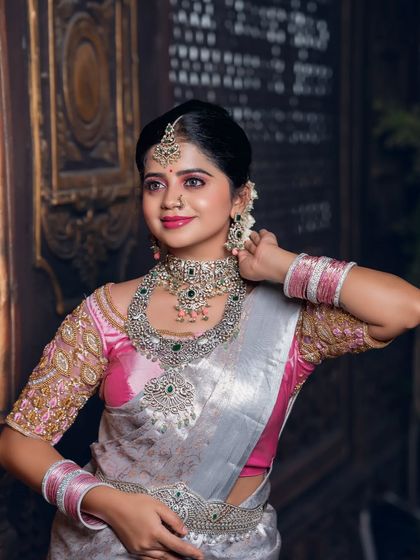 A three-quarter view of the model, showing the full set of diamond and emerald jewellery against the silver saree.