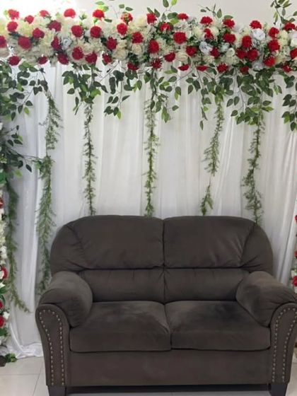 A beautiful floral frame made of red and white roses against a simple curtain backdrop. This setup is perfect for creating a photo booth or a small stage for an engagement or anniversary at home.