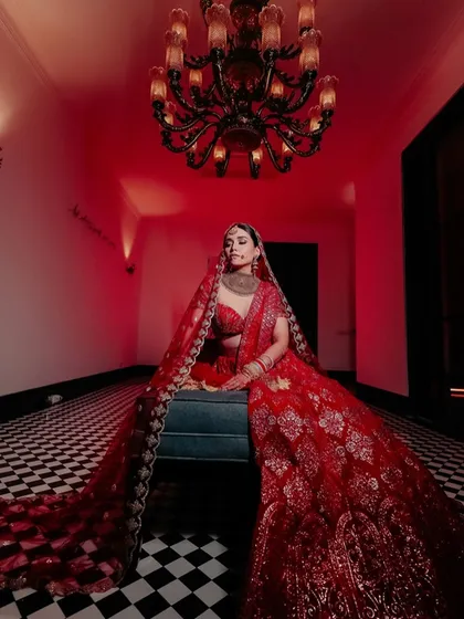 A full-length portrait of the bride seated, looking like a queen in her red attire.