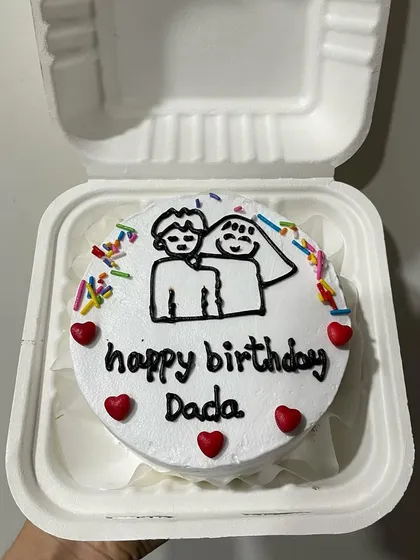 A similar couple drawing on a bento cake, this time for 'Dada' (brother or grandfather), decorated with red hearts and sprinkles.