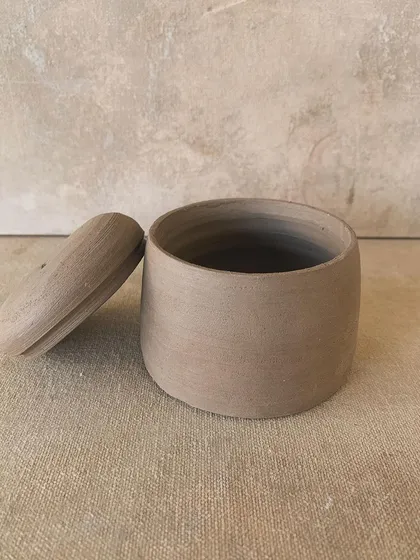 A beautifully thrown lidded jar, unglazed, showing the subtle throwing rings from the wheel.