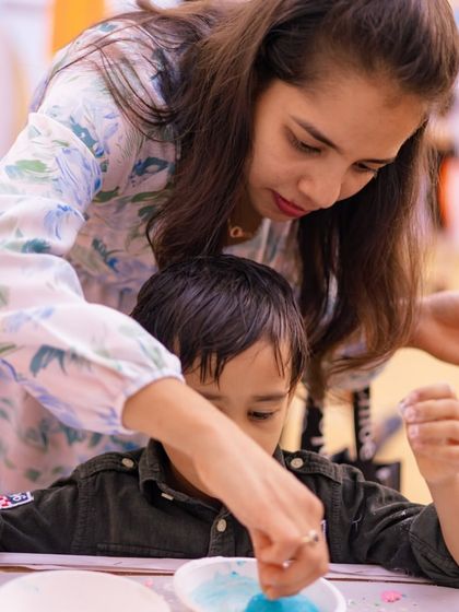 A mom helps her son with a sand art activity at one of the creative corners. I ensure there are quieter activities for kids who need a break from the high-energy fun.
