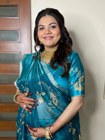 A full-length view of this beautiful mom-to-be. Her elegant blue saree is paired with soft makeup and a classic half-up hairstyle, making her look and feel special for her baby shower.