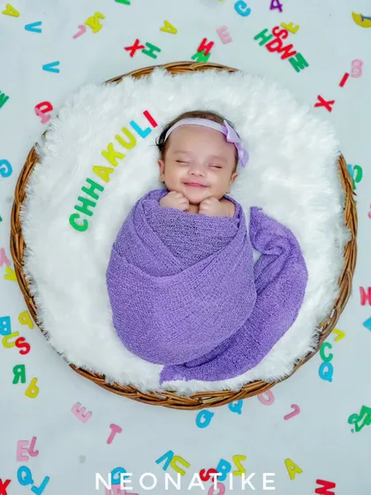 A smiling, sleeping newborn in a basket, with her name spelled out. A wonderful way to personalize your baby's first photos.