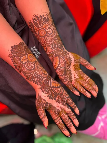A top-down view of the completed design, showing the symmetry and detail on both hands. The mix of bold leaves and fine lines is characteristic of this style.