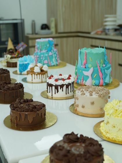 A beautiful assortment of cakes from a recent masterclass, featuring drip cakes, mermaid-themed tiers, and other creative designs. This shows the range of styles you will learn to master.