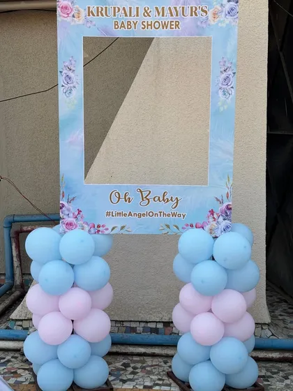A close-up of the personalized 'Oh Baby' selfie frame, supported by pastel pink and blue balloon columns.