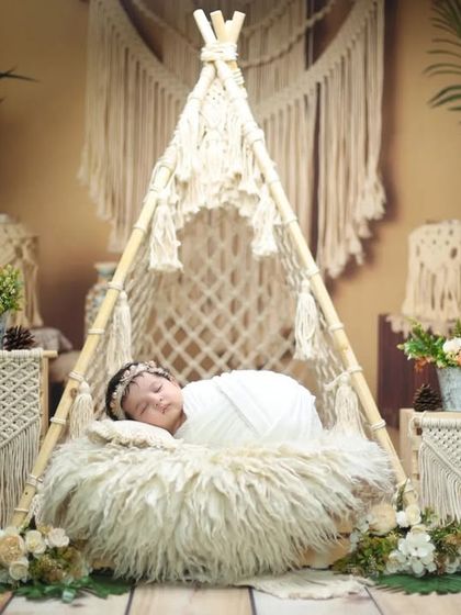A serene newborn nestled inside a macrame teepee. This shot highlights the cozy and safe space we create within our larger boho-chic arrangements.
