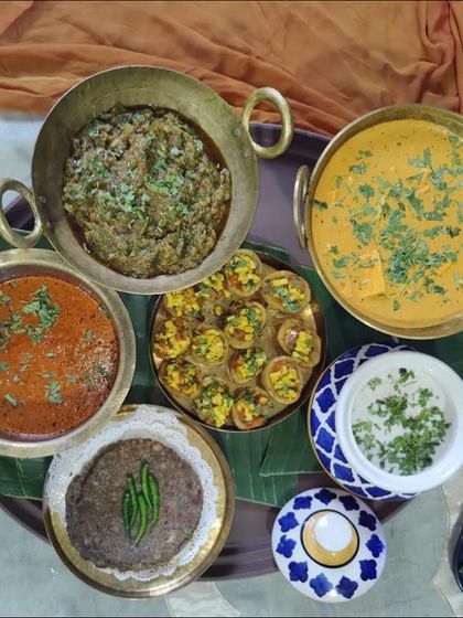 A complete Navratri meal spread, featuring a variety of curries, raita, roti, and appetizers. We use traditional brass and ceramic serveware to enhance the authentic dining experience.