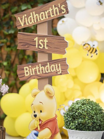 A personalized wooden sign for Vidharth's 1st Birthday, perfectly matching the rustic, charming feel of the Winnie the Pooh theme.