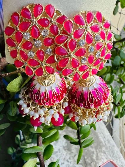 These rani pink meenakari jhumkas are a crowd favorite. The bright pink floral top is paired with a beautifully painted dome, making it a perfect match for lehengas and suits.
