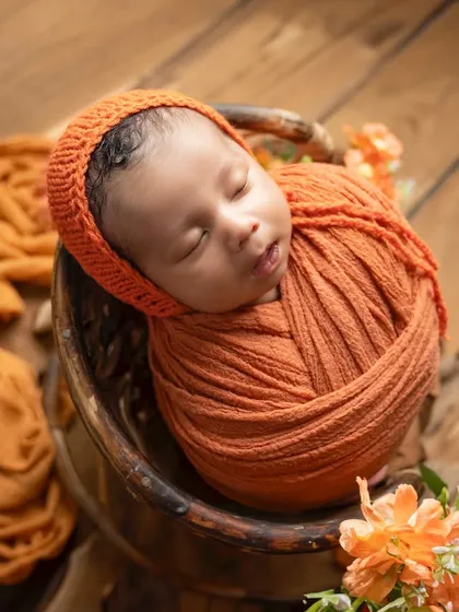 An angled shot showing the newborn nestled in a bowl on a rustic wooden background, highlighting the textures and warm tones of the setup.