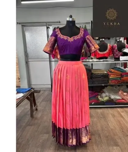 A stunning lehenga set on display in my studio. This piece combines a rich purple blouse with traditional gold borders and a bright pink pleated skirt, showcasing a classic color combination.