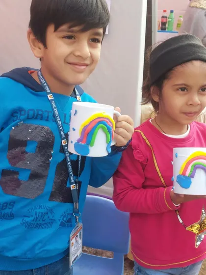 Two friends proudly show off the matching rainbow mugs they created at our stall. Crafting together is a wonderful way for children to bond and share a creative experience.