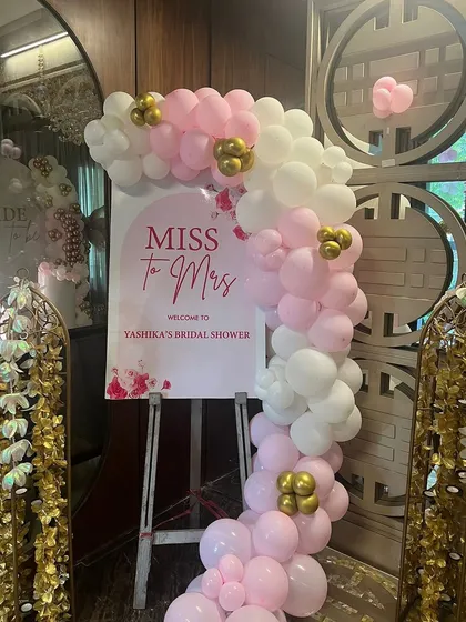 A lovely welcome sign for a 'Miss to Mrs' bridal shower. The personalized sign is adorned with a pink and white balloon garland, setting a sweet and celebratory tone for the event.