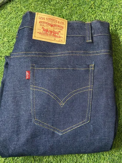 A freshly stitched pair of classic dark wash jeans, featuring the iconic leather patch and red tab detail, made to the client's exact waist and length.