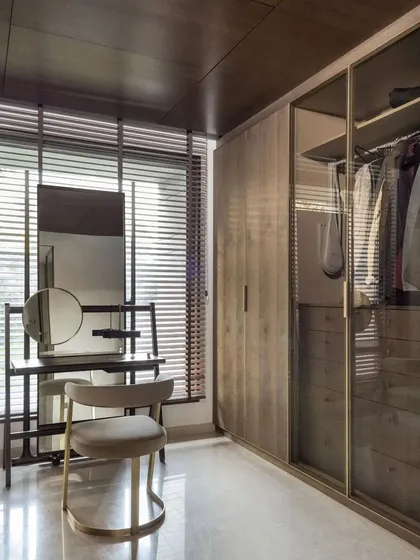 A custom vanity table and floor-to-ceiling glass wardrobe in a walk-in closet. The design maximizes storage and style, with integrated lighting and brass-framed details.