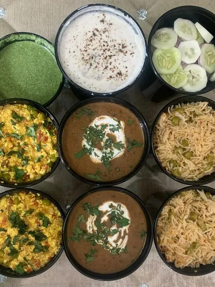 A beautiful display of a bulk order before packing. This order included Dal Makhni, Paneer Bhurji, Veg Pulao, Raita, and salad, served in individual bowls.