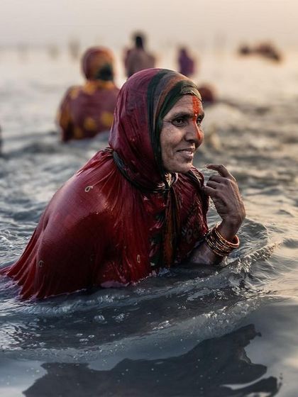 A woman emerges from the river after her holy dip during Chhath, her smile reflecting a sense of spiritual fulfillment and joy.