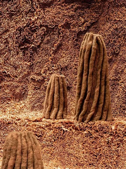 A close-up of the textured landscape in the 'Shroom' installation. The organic, vertical forms rise from a bed of equally intricate textile work, creating a unified and immersive environment.