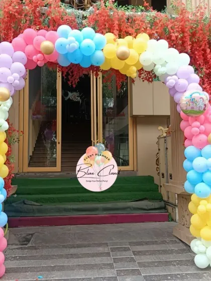 A rainbow-colored balloon arch creating a cheerful entrance for an outdoor party.