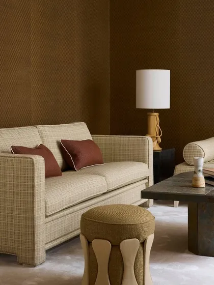 An intimate seating area featuring a Nobilis sofa in a tactile, textured fabric. The earth-toned palette, combined with sculptural forms like the unique ottoman, creates a grounded and serene atmosphere, reflecting our focus on creating spaces of quiet elegance.