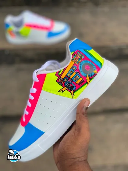 A hand-held shot of the boombox side of our custom Campus shoes. The retro boombox is painted with vibrant neon colors and lightning bolts.