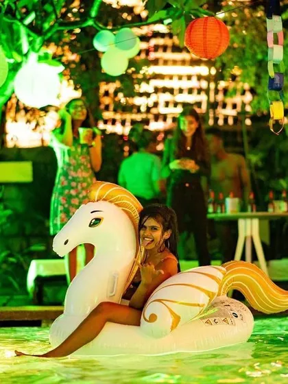 A guest riding an inflatable unicorn at the pool party.