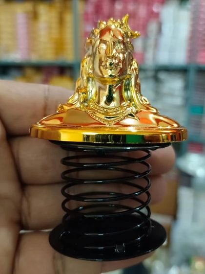 A close-up of the golden car dashboard spring idol of Lord Shiva, a popular item for adding a touch of divinity to your vehicle.