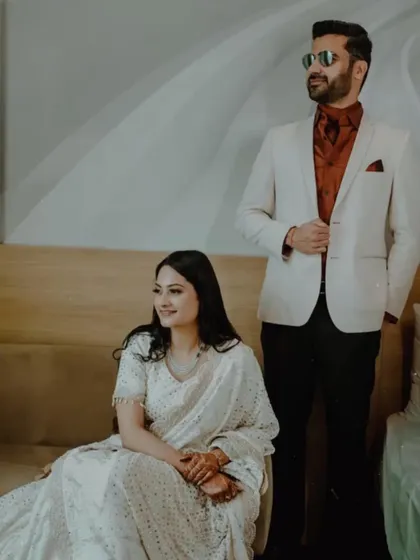 A chic, posed shot of the couple indoors, showcasing their stylish, coordinated white and red outfits for a sophisticated engagement look.