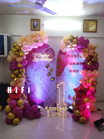A sophisticated birthday setup with two arched backdrops and a beautiful magenta and gold balloon arrangement.