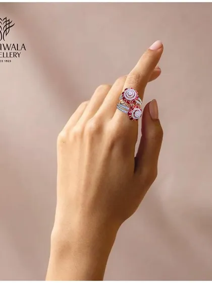 A model's hand displays a unique double-headed ring with swirling patterns of rubies and diamonds, showcasing its playful yet elegant design.