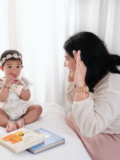 A mother playing peek-a-boo with her baby. My sessions are child-led, which means we always make time for games and fun.