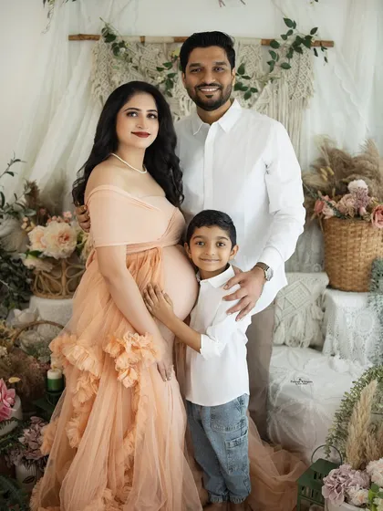 A complete family portrait filled with warmth and happiness. The older brother stands proudly with his parents, all of them sharing in the excitement of the new arrival.