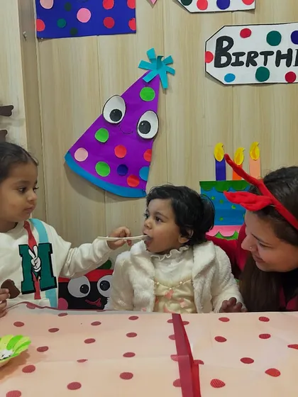 Another friend gets to share in the cake-feeding fun, with a teacher looking on with a smile.