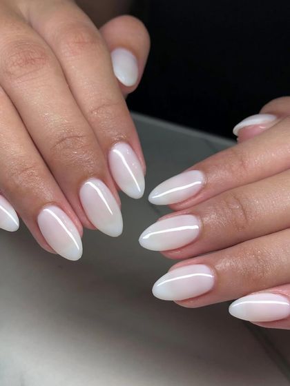 A simple yet stunning set of natural-looking gel nail extensions. The milky white finish on these almond-shaped nails is perfect for an understated, elegant style.